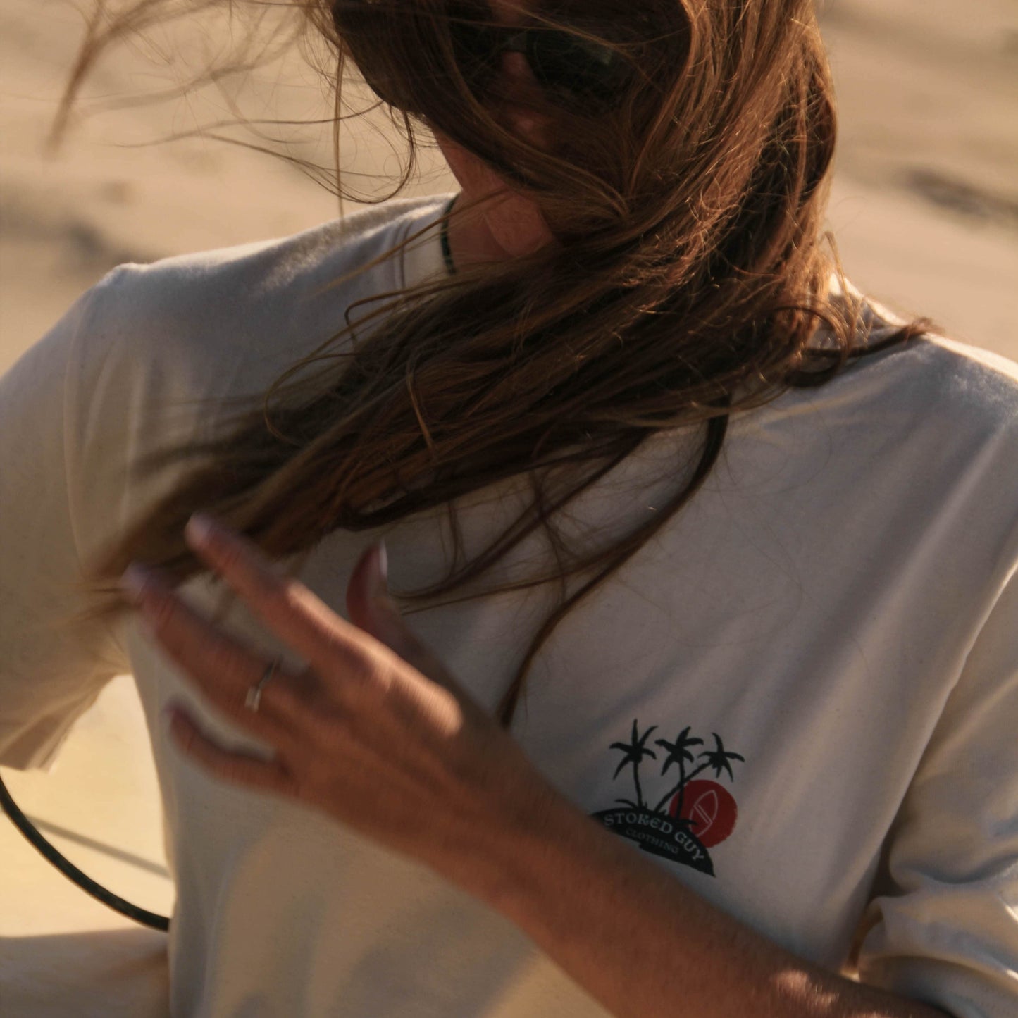 Person wearing a white t-shirt with a graphic design, standing outdoors.