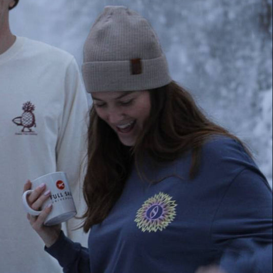 Three people standing in a snowy forest, holding cups.