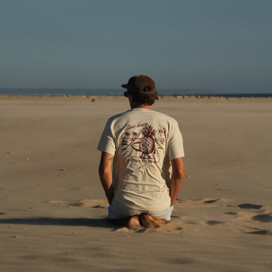 Person sitting on a sandy beach looking out towards the ocean