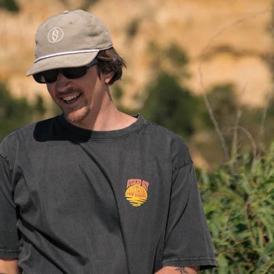 Man wearing a cap and sunglasses with a blurred natural background