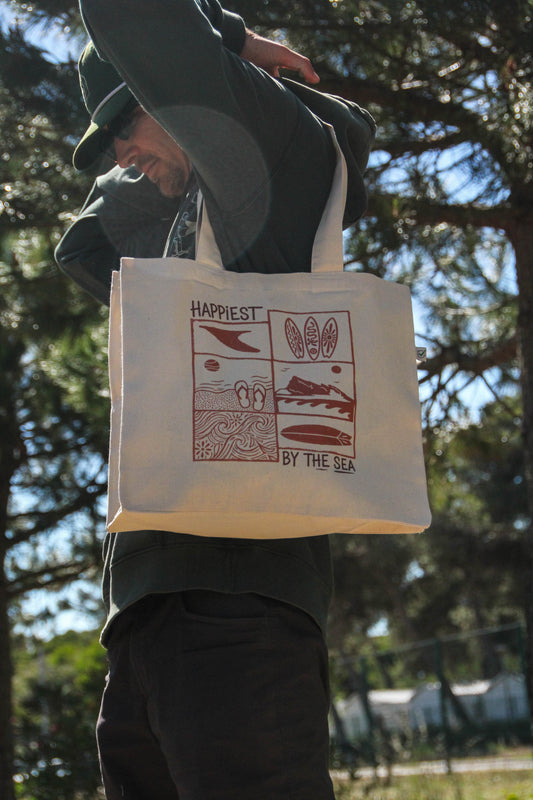 Person holding a tote bag with illustrations and text outdoors