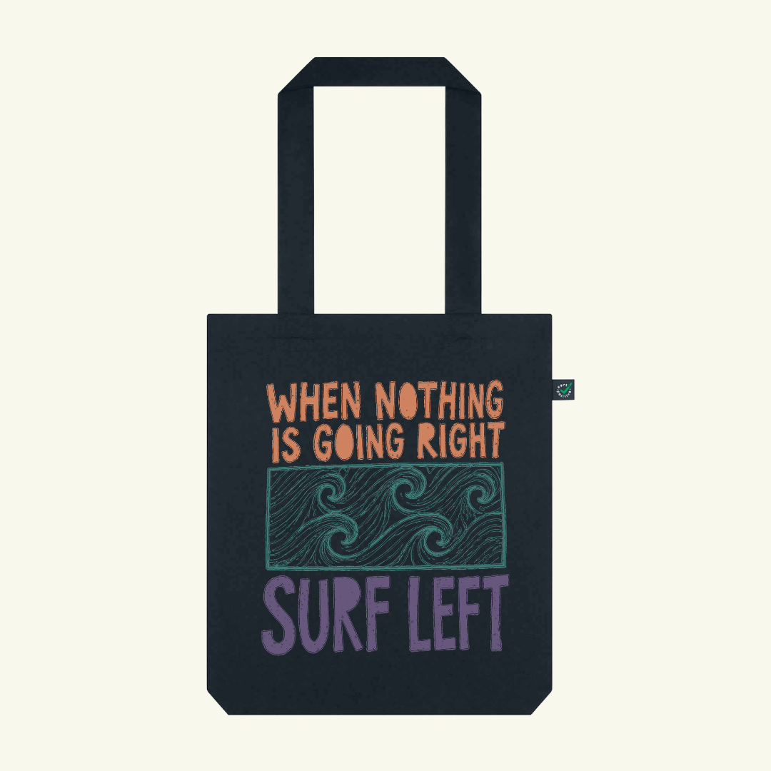 Black tote bag with motivational quote and wave design on a white background