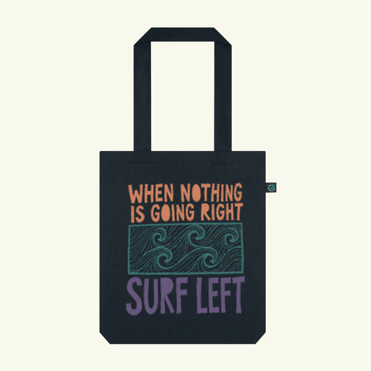 Black tote bag with motivational quote and wave design on a white background