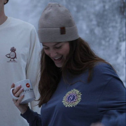 Three people standing in a snowy forest, holding cups.