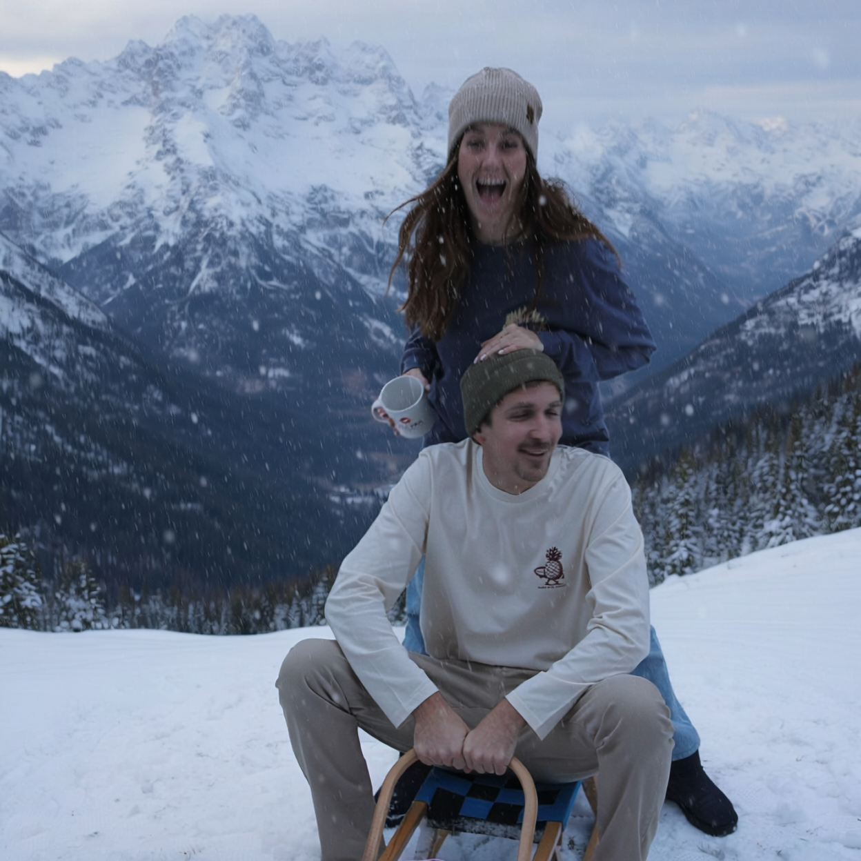Two people sitting on a sled in a snowy mountain landscape