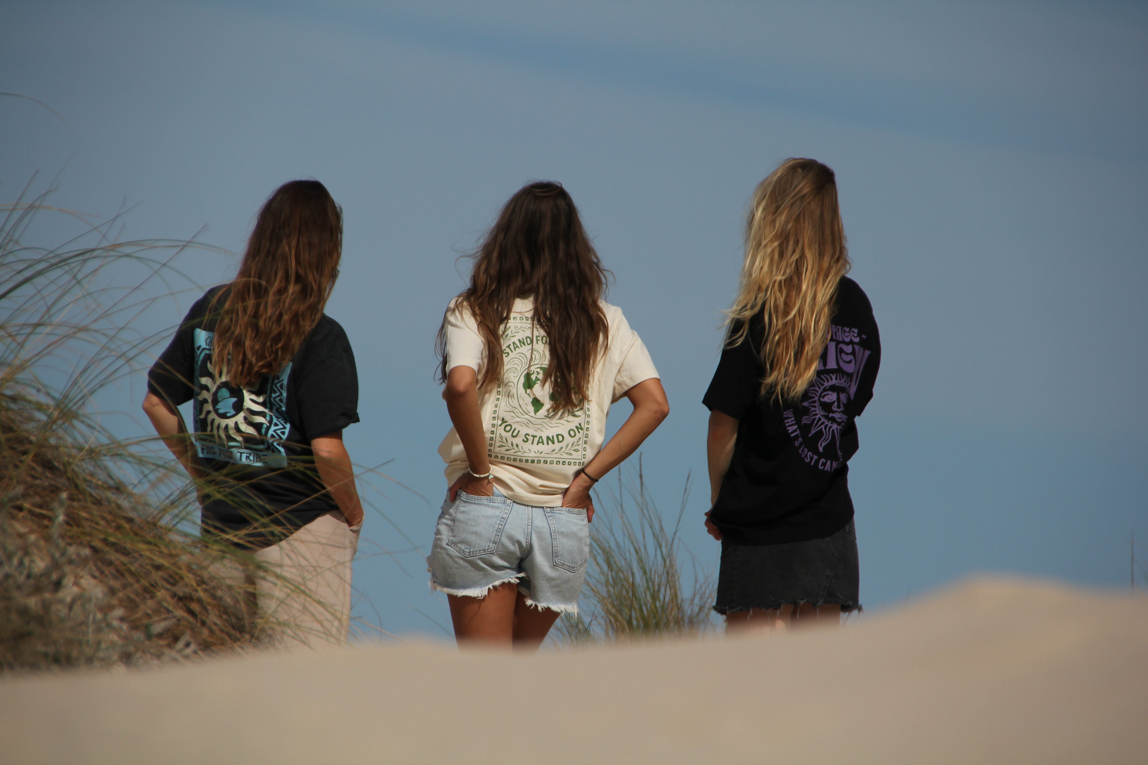 Three people standing on a beach with a clear sky