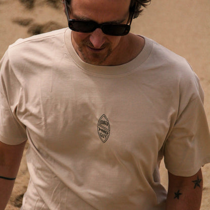 Man wearing a beige t-shirt with a logo in a desert setting