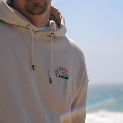 Person wearing a beige hoodie with 'Stoked Guy Clothing' logo against a blurred natural background