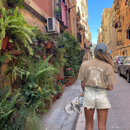 Person walking down a narrow street lined with plants and buildings