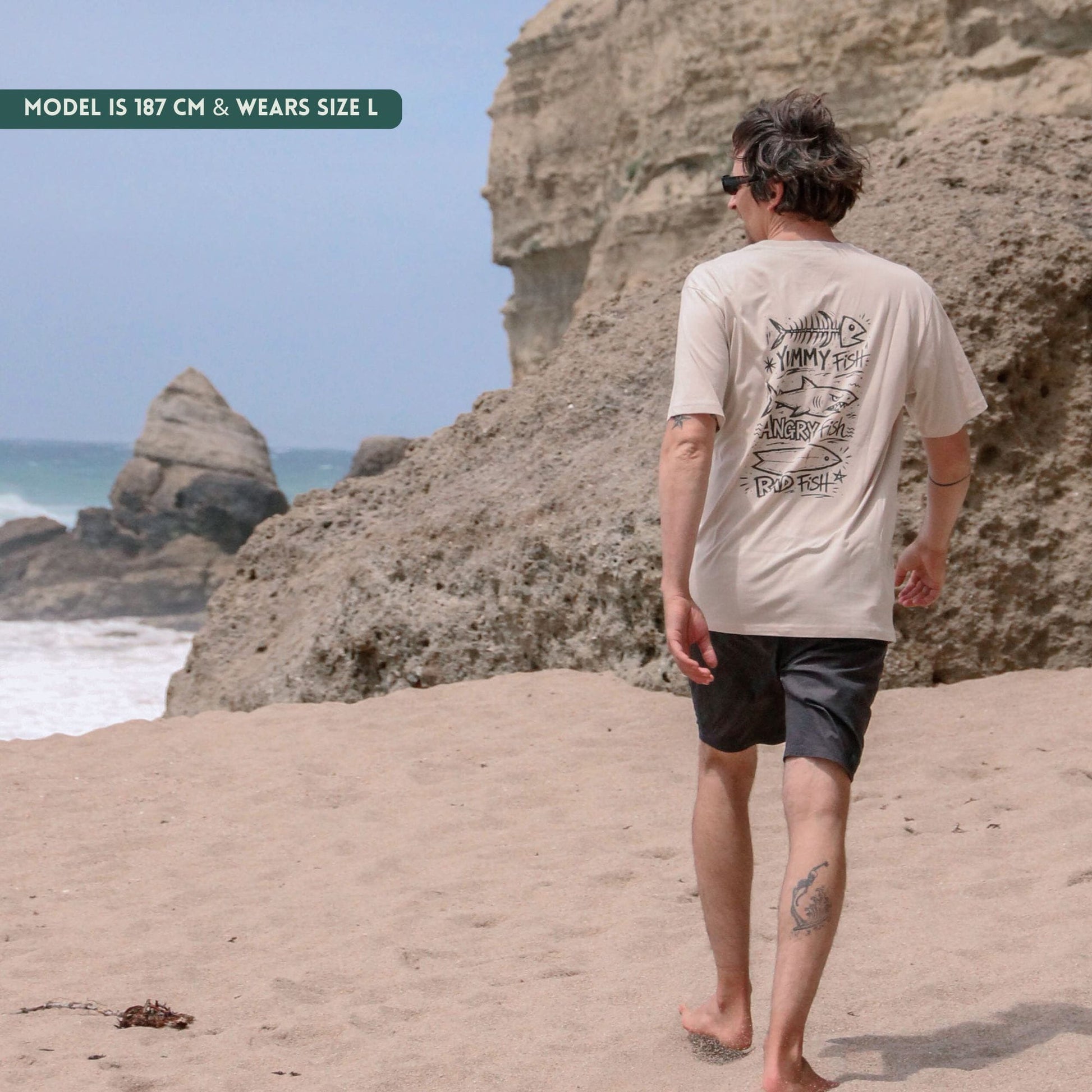 Man walking on a beach with cliffs and ocean in the background